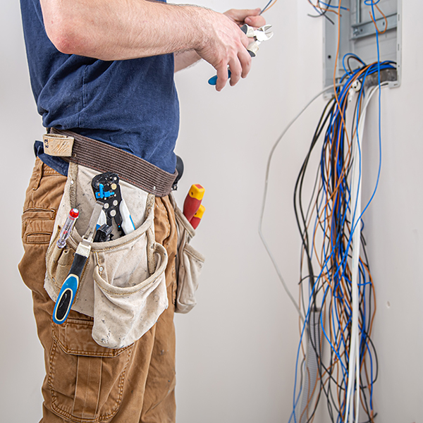 electrician builder work examines cable connection electrical line fuselage industrial switchboard professional overalls with electrician s tool